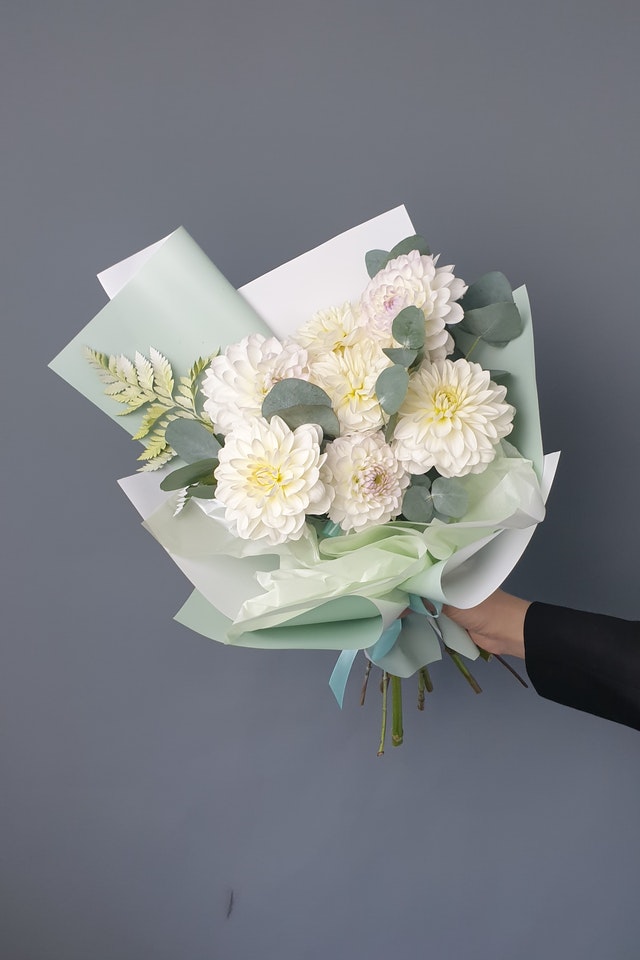 A Person Holding a Bouquet of White Dahlias with Eucalyptus Leaves