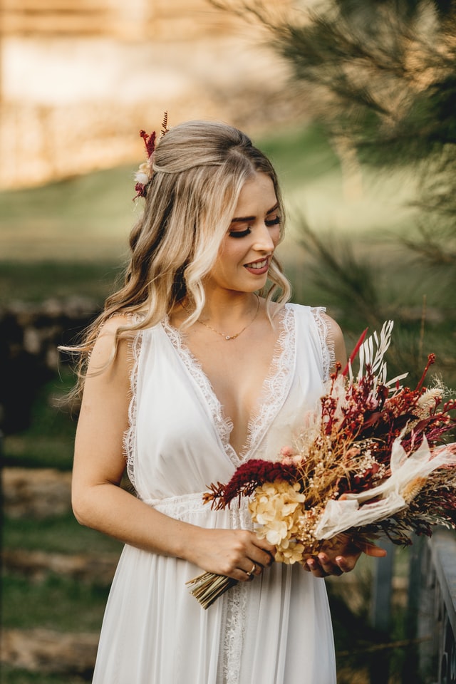 Bride holding a dried  burgundy flowers bouquet